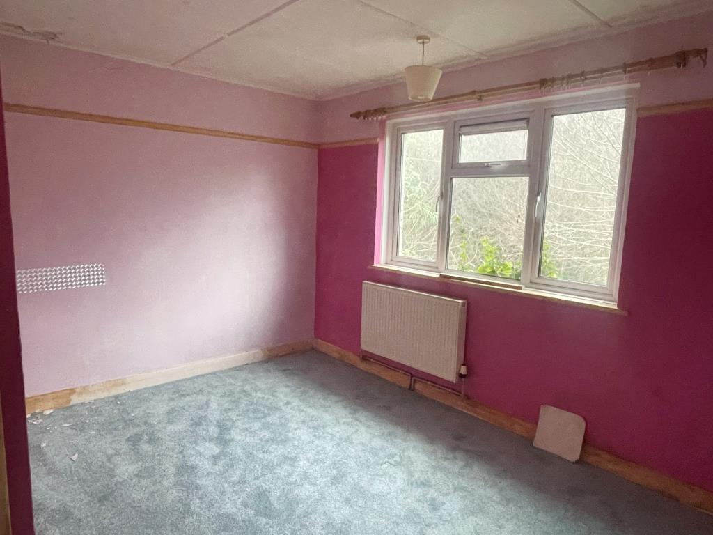 Lot: 119 - ONE-BEDROOM BUNGALOW - Bedroom with radiator and window looking out to rear